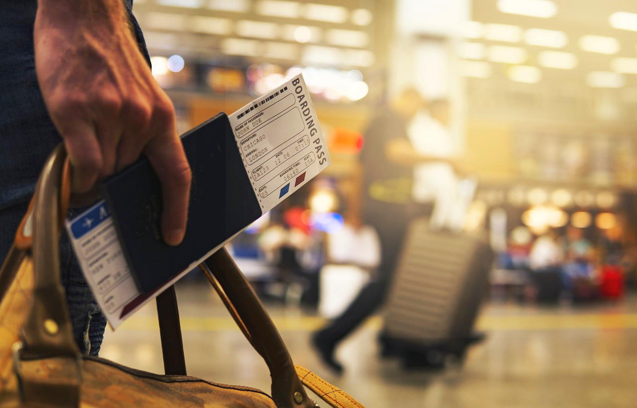 Close-up of a boarding pass being carried through a busy airport.