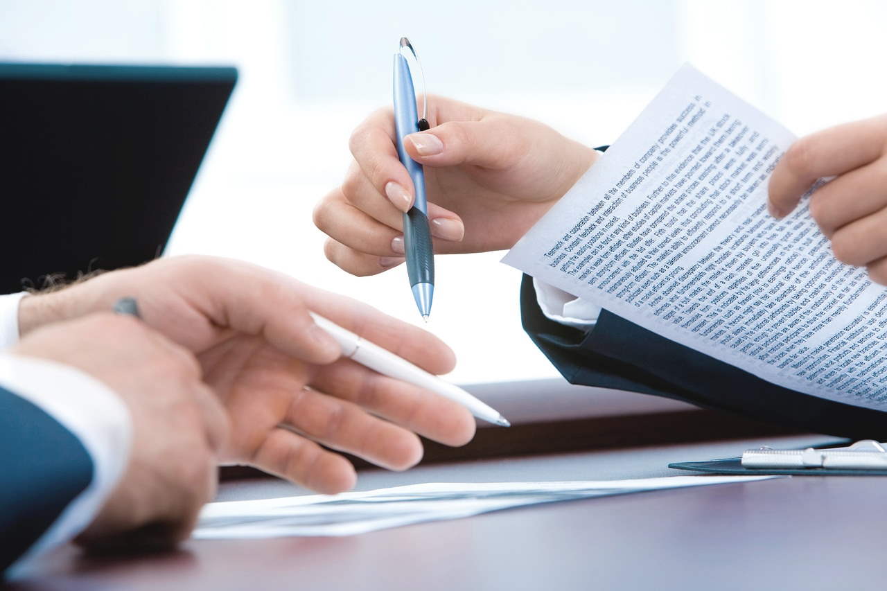 Two people's hands shown working on important documents.