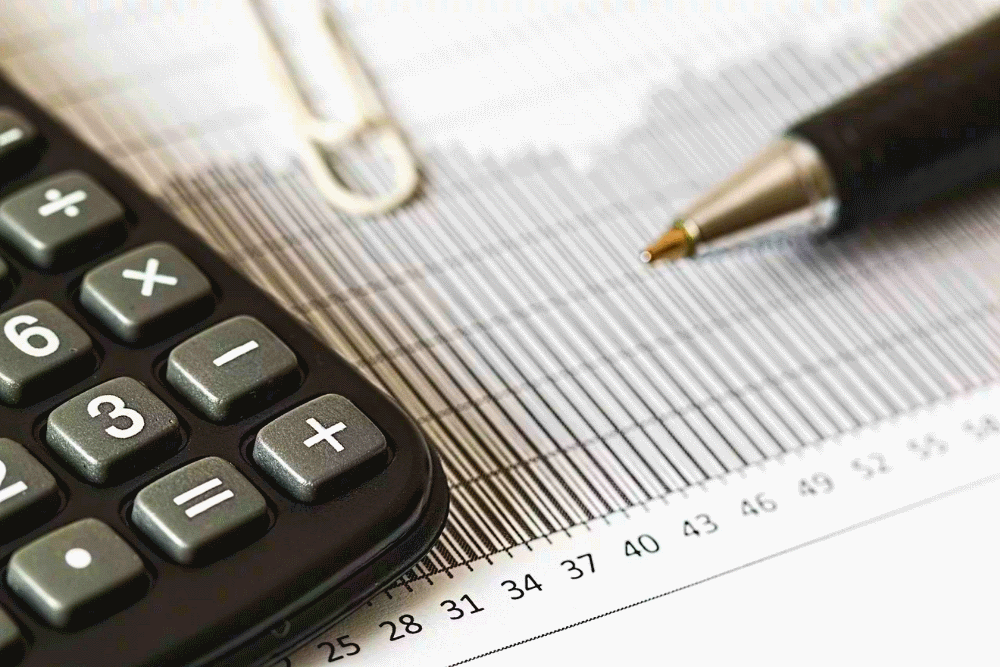 Closeup photo of a document, a calculator, and a pen.