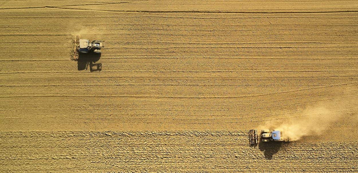 Tractors working on a brown field.