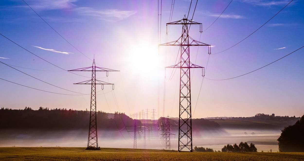 Powerlines against a blue sky and a setting sun