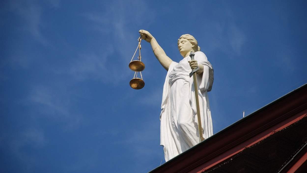 Statue symbolizing justice against a blue sky