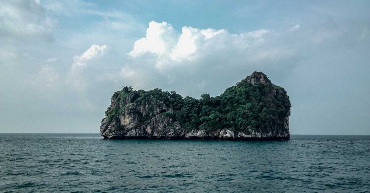 Island against a blue sky and calm ocean.