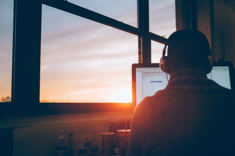 Employee in front of his laptop, looking into the sunset