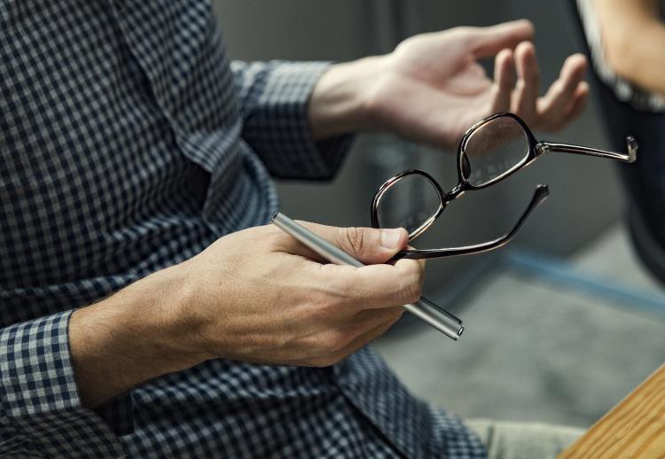 Man sitting at his desk holding glasses