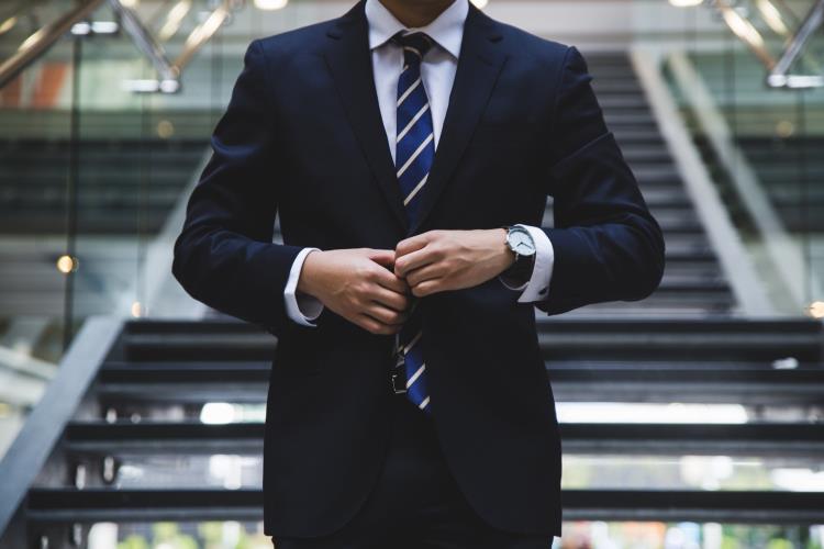 Neatly dressed man adjusting his suit buttons