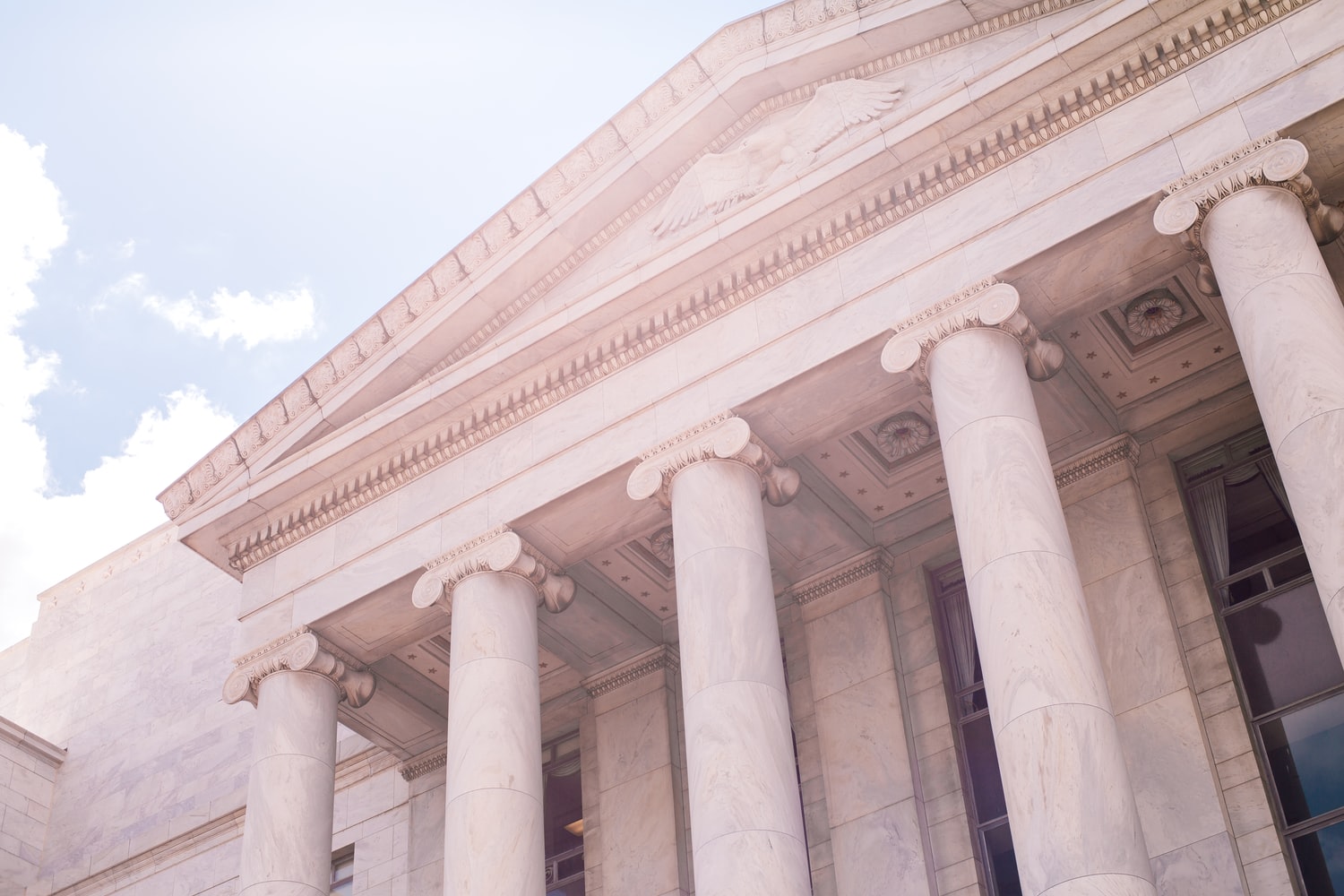 Classical style government building with pillars, and a blue sky behind.