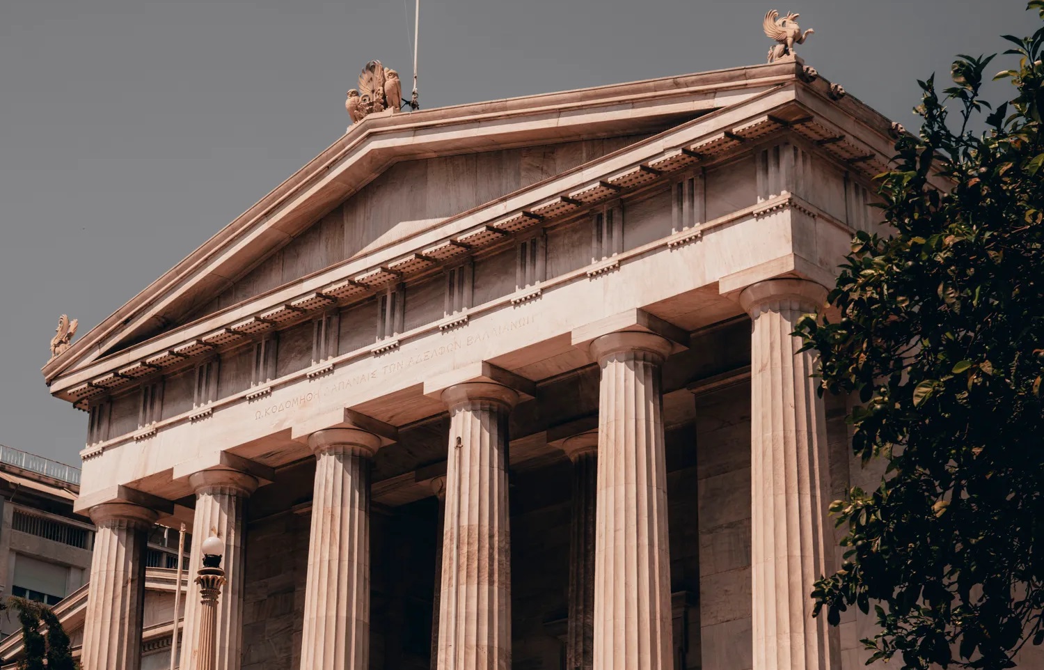 Classical columns of a government building, with a dramatic, cloudy sky behind.