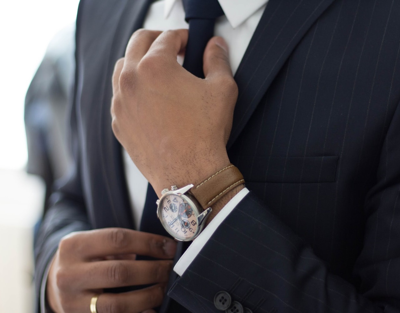 A man in a suit adjusting his tie