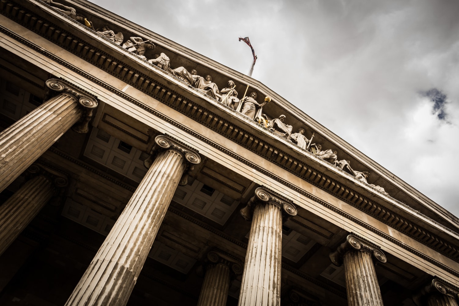 Low angle photo of an ornate court building, with sculptures and pillars, against a slightly cloudy sky.