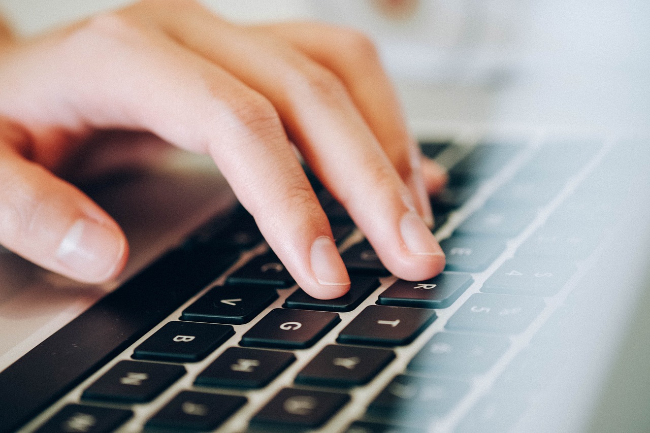 Closeup photo of a person's hand over a laptop keyboard.